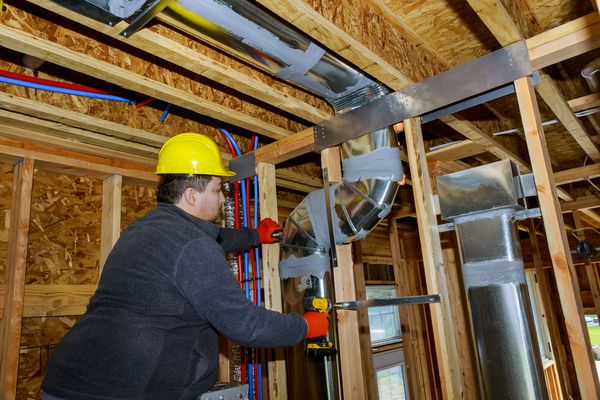 An HVAC specialist installing air ducts into a new home build.